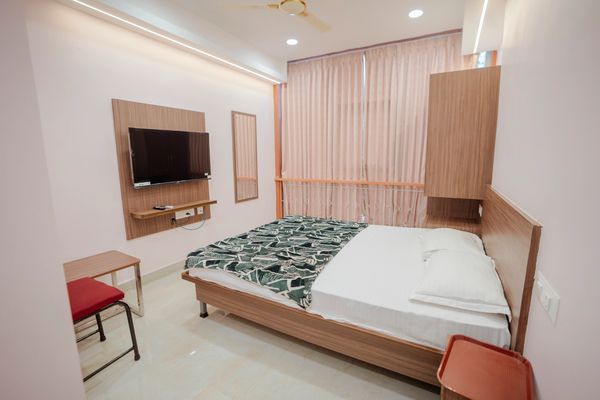 Minimalist bedroom with wooden furniture and TV.