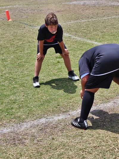 Two boys resting during a sports game on a grass field.