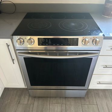 Modern stainless steel electric stove with glass cooktop in a kitchen.