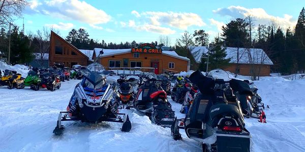 Dozens of snowmobiles parked at Crane Lake Bar and Grill in the winter.