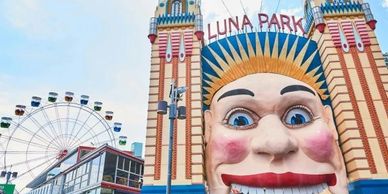 Entrance to Luna Park amusement park with a giant face and ferris wheel.