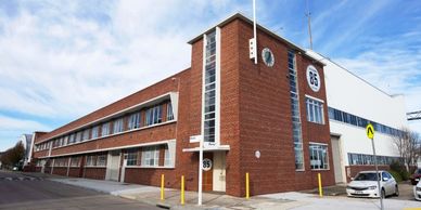 A large brick and white industrial building under a partly cloudy sky.