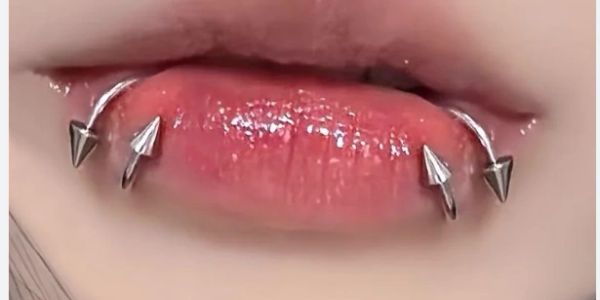 Close-up of lips with silver spike piercings.