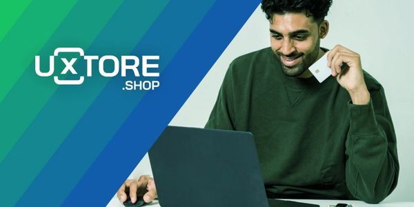 Rapaz comprando portando um cartão de crédito na mão e olhando feliz para o computador