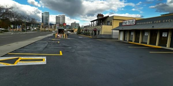 Empty parking lot near urban buildings under partly cloudy sky.