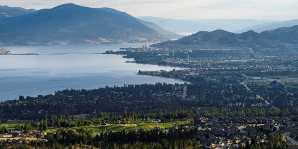 Cityscape by a large lake with mountains in the background.