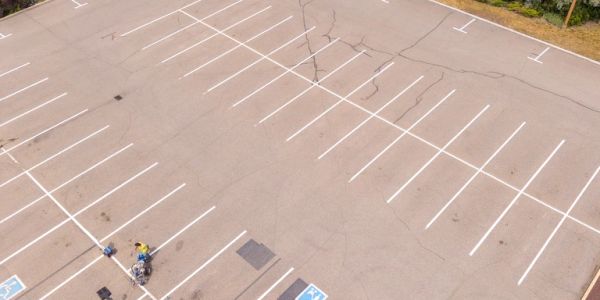 Empty parking lot with one person on a motorcycle.