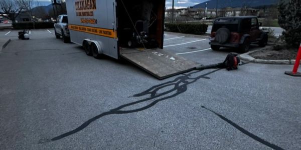 Black sealant spreads from a trailer ramp onto asphalt.