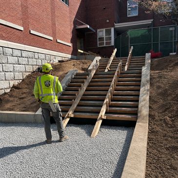Construction worker inspects wooden stair frame at building site.