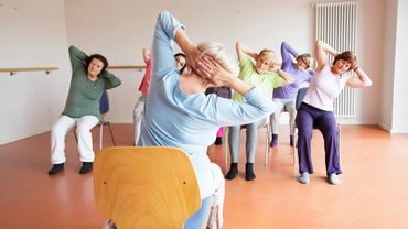 A group of elderly women exercising while seated on chairs.