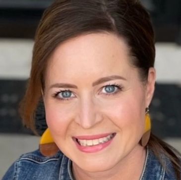 Smiling woman with blue eyes and colorful earrings.