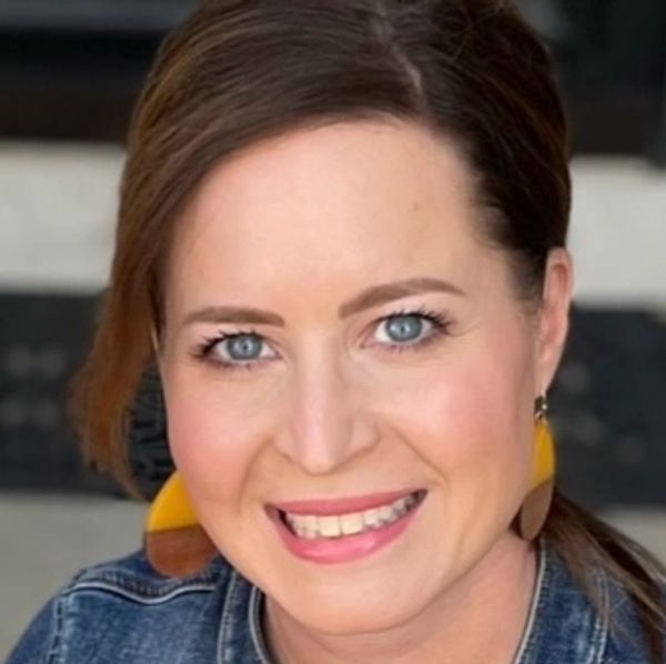 Smiling woman with blue eyes and colorful earrings.
