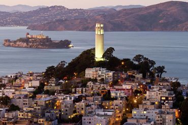 Evening view of Coit Tower overlooking San Francisco Bay and Alcatraz Island.