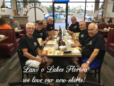 Group of older men in matching shirts dining together in a restaurant.