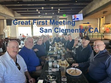 Group of men gathered around a long table at a restaurant for a meeting.
