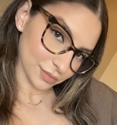 Close-up portrait of a woman wearing tortoiseshell glasses and subtle makeup.