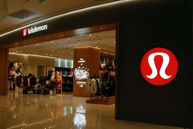 Lululemon store entrance with illuminated signs and mannequins.
