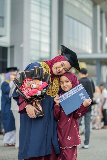 Graduate posing with young family member
