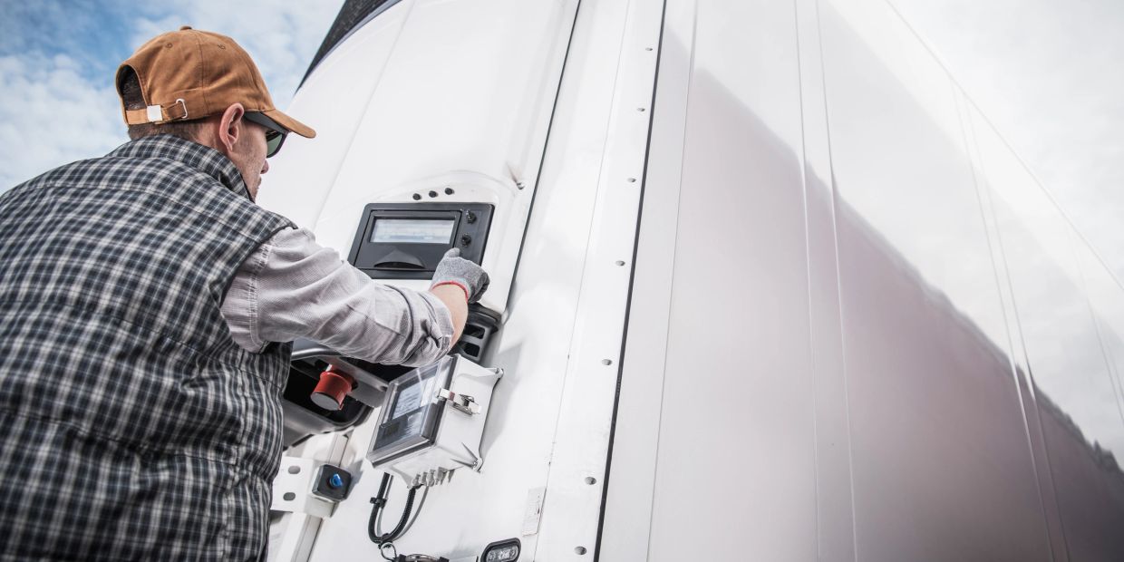 Worker operating a control panel on a large white machine or vehicle.