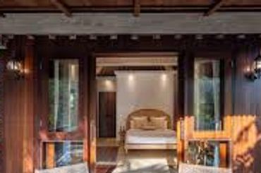 Cozy wooden porch with two chairs and a view into a bedroom.