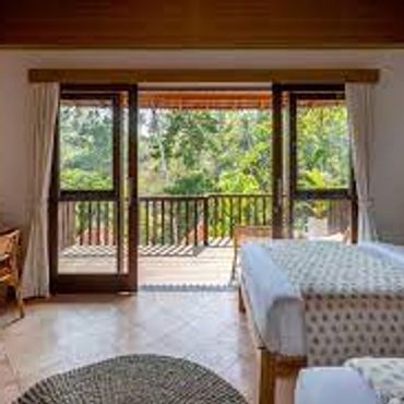 Cozy bedroom with twin beds opening to a balcony with lush greenery.