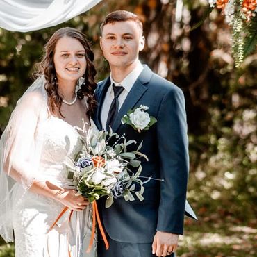 A happy bride and groom posing outdoors on their wedding day.