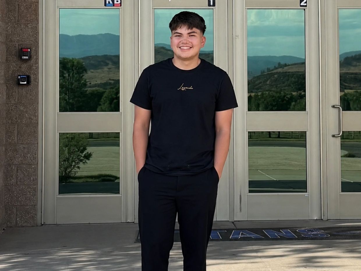 Smiling young man in black standing outdoors.