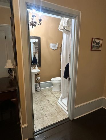 Great lighting bathroom with beige walls, a white pedestal sink, and a shower with white curtains.