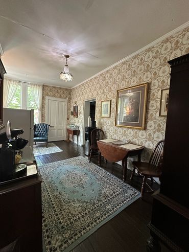 Vintage dining room with patterned wallpaper, ornate chandelier, and classic furniture.