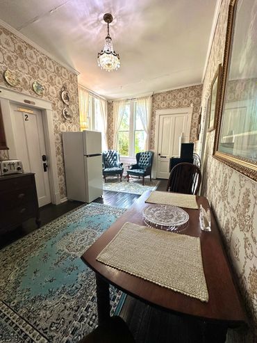 Cozy vintage room with patterned wallpaper, blue armchairs, and classic decor.