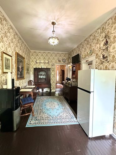Vintage kitchen with ornate wallpaper, wooden furniture, and a chandelier.