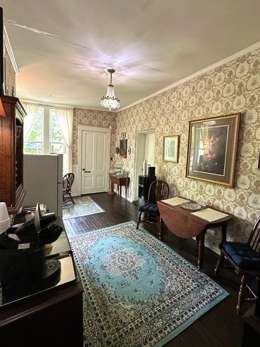 Vintage dining room with patterned wallpaper and crystal chandelier.