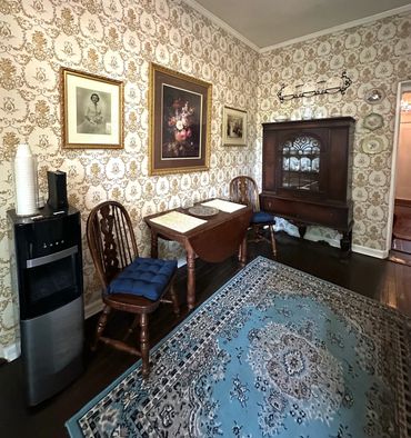 Vintage dining room with ornate wallpaper and classic wooden furniture.
