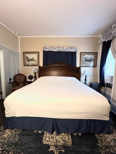 Traditional bedroom with a large bed and horse-themed artwork.