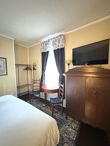 Cozy room with vintage furniture, curtains, and a wall-mounted TV.