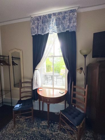 Cozy room with vintage wooden chairs and a small table by a window with dark curtains.