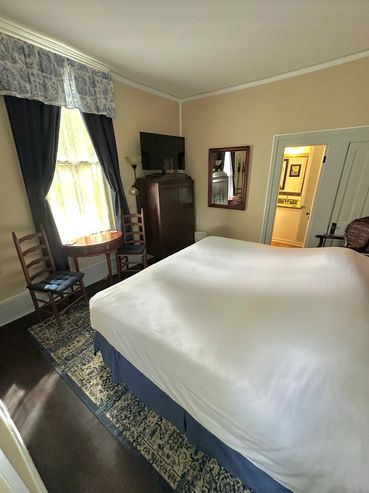 Cozy bedroom with a large bed, wooden furniture, and a window with curtains.