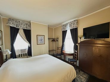 Cozy bedroom with a large bed, antique furniture, and dark curtains.