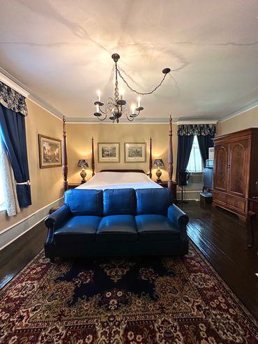 Elegant bedroom with a four-poster bed, blue leather sofa, and vintage decor.