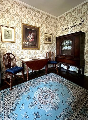 Cozy vintage dining corner with wooden furniture and floral wallpaper.