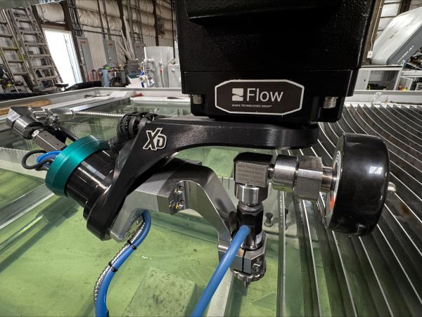 Close-up of Flow X5 waterjet cutting head in an industrial setting.