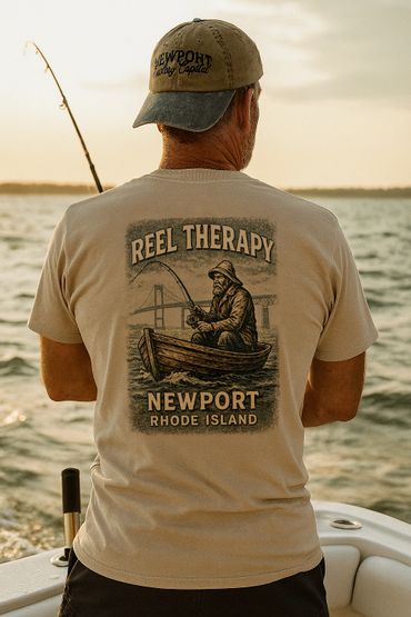 Man fishing on a boat wearing a "Reel Therapy" Newport Rhode Island shirt at sunset.