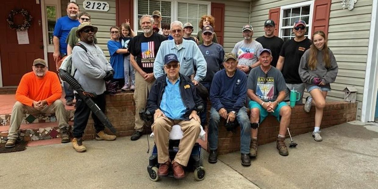 A diverse group of people gathered outside a house, posing for a group photo.