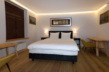 main bedroom with hotel king size bed and two wooden desk / tables