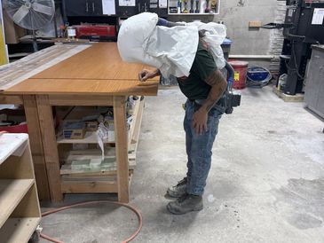 Finisher inspecting a veneer panel under raking light before coating