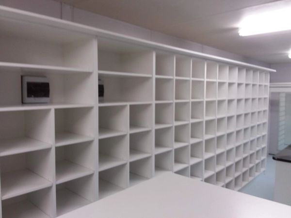 Large wall of white cubby shelving units in a commercial or storage fitout.