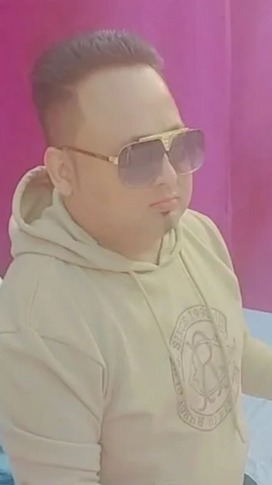 Man in sunglasses playing a red keyboard indoors.