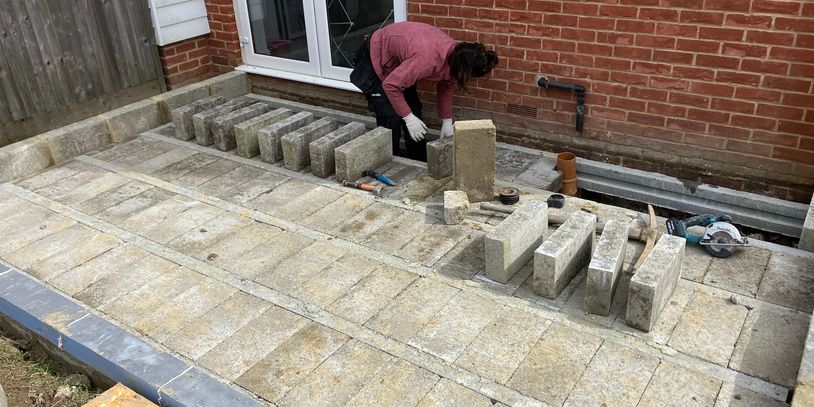Person laying stone pavers in backyard.