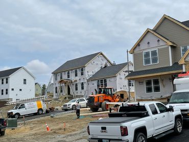 New houses under construction with workers and machinery on site.