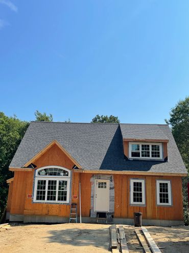 A wooden house under construction with new windows and roof.